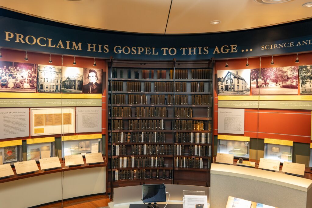 Mott Gallery bookshelf featuring early editions of "Science and Health with Key to the Scriptures" at Longyear Museum in the main "Mary Baker Eddy: A Spiritual Journey" exhibit