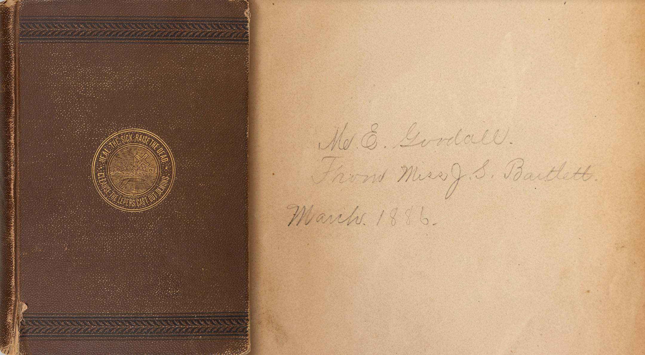 A copy of "Science and Health with Key to the Scriptures," by Mary Baker Eddy, given by Julia Bartlett to Mary Goodall in 1886. It has a brown cover and a golden seal with the words "Heal the sick. Raise the dead. Cast out demons. Cleanse the lepers." The note inside is in pencil and reads: "M.E. Goodall. From Miss J.S. Bartlett. March 1886."