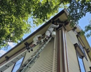 Painting crew on ladders at Mary Baker Eddy historic house, Lynn, Massachusetts work on the trim of the Victorian home.
